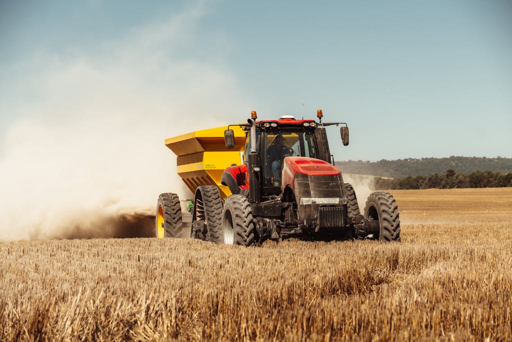 A powerful red and yellow tractor working in a sunny wheat field, symbolizing modern farming techniques.